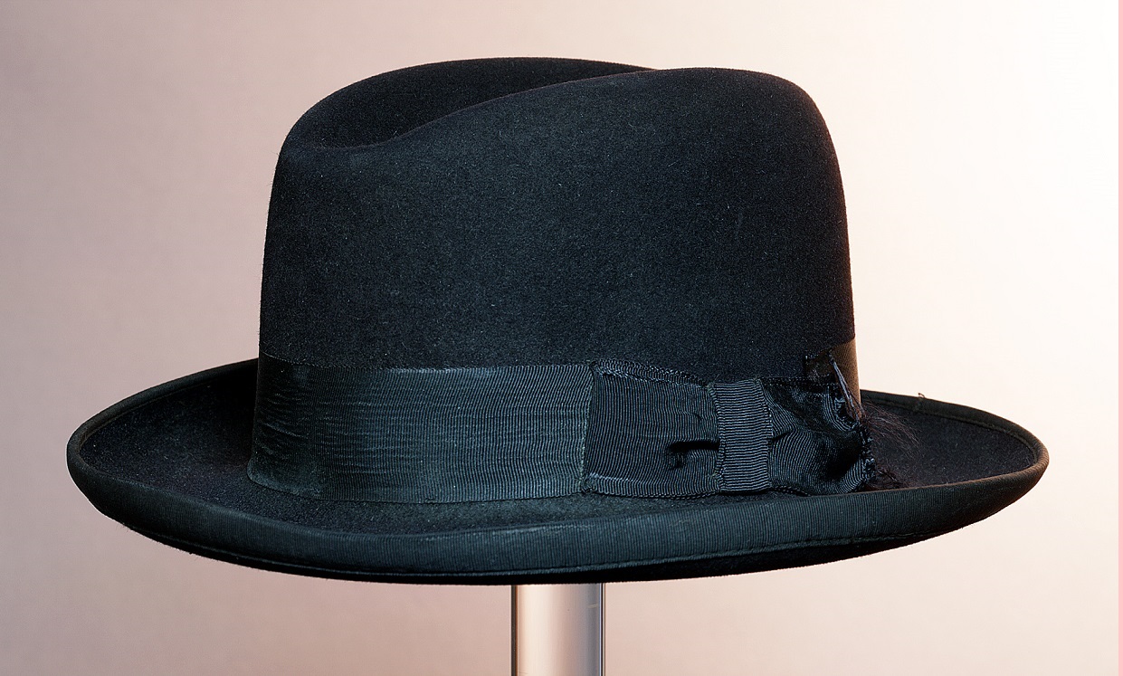 The-Homburg. AuthorMuseum Rotterdam. Creative Commons license. https://commons.wikimedia.org/wiki/File:Zwarte_Homburghoed_of_gleufhoed,_met_opstaande_rand_en_ripslint,_leren_entree,_deuk_midden_in_bol,_objectnr_21588.JPG